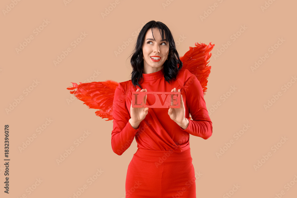 Obraz premium Beautiful young happy woman dressed as cupid with word LOVE on beige background. Valentine's Day celebration
