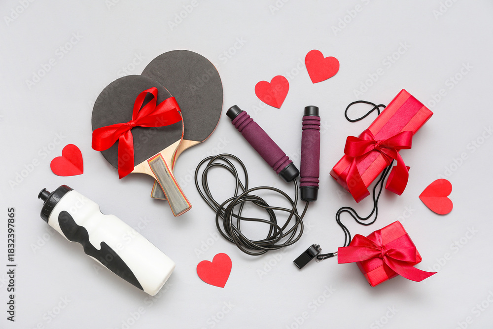 Naklejka premium Composition with sports equipment, gifts and red paper hearts for Valentine's Day celebration on grey background