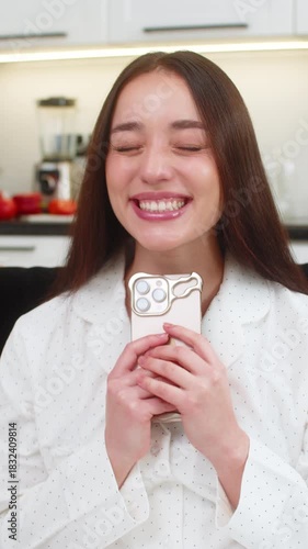 Young woman at home reads smartphone message with good news jumps with joy smiles celebrates win. Caucasian girl on sofa holds mobile phone raises fist shows victory sign excited reaction very glad
