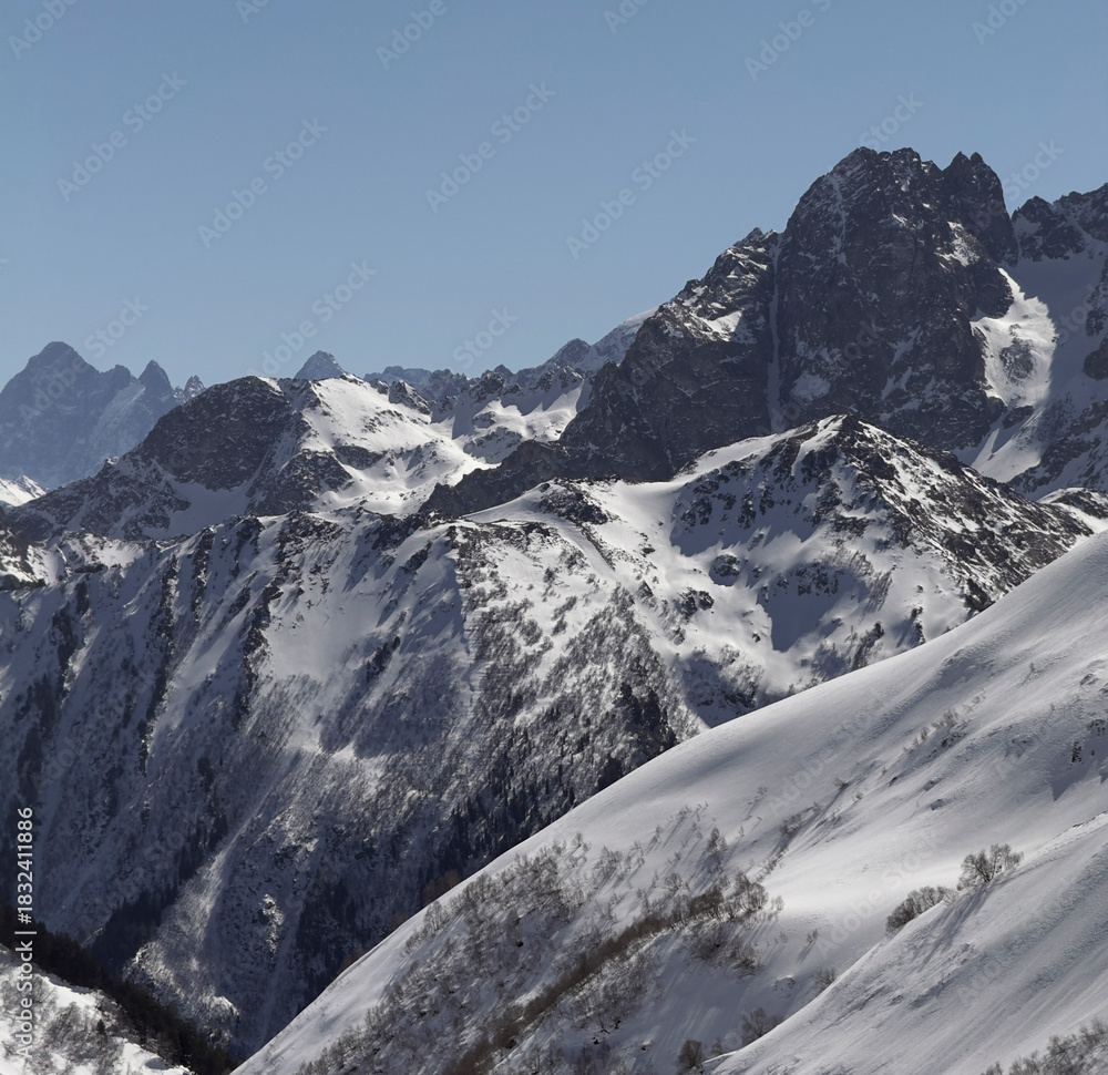 Obraz premium Majestic snow-covered peaks rise under a clear blue sky, showcasing winter's beauty