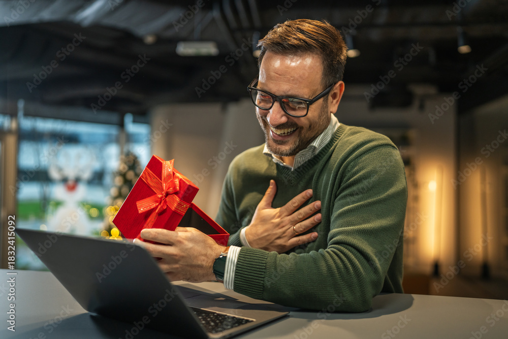 Fototapeta premium Man smiling receiving christmas gift during video call
