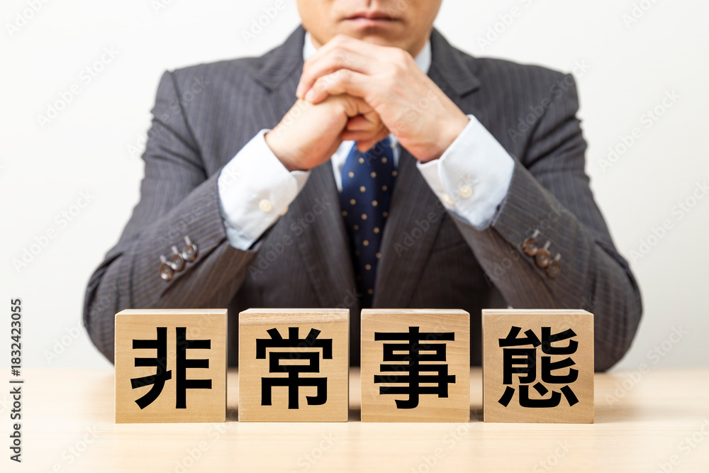 Obraz premium 「非常事態」と書かれたブロックとビジネスマン