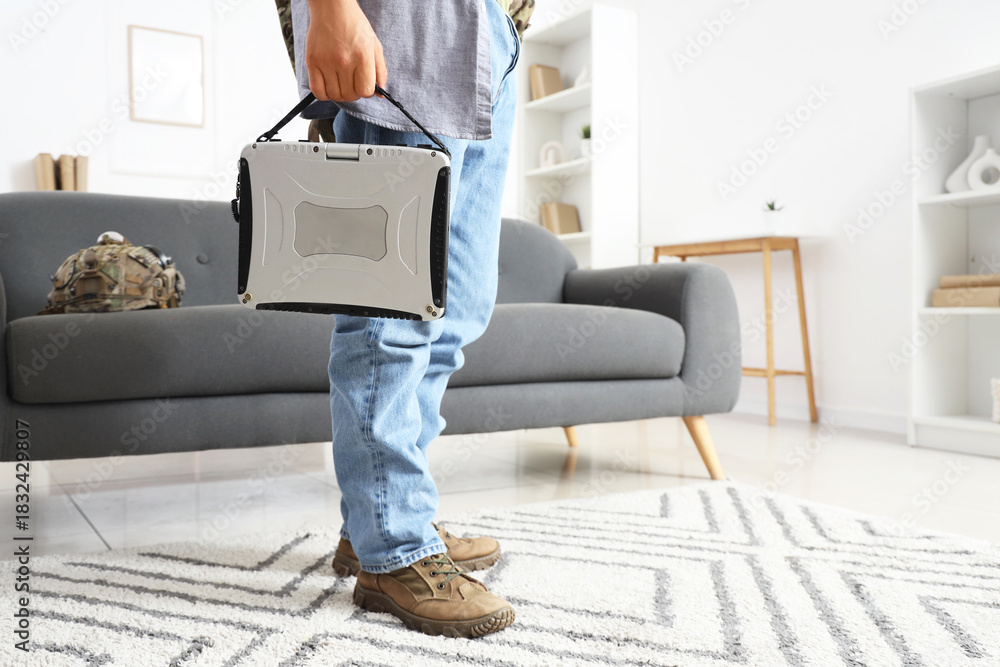 Naklejka premium Young soldier with military laptop at home