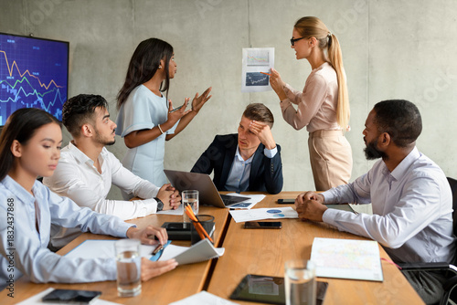 Bild auf Leinwand Two female employees are arguing during a corporate meeting as a multiethnic group of colleagues observes