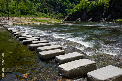 Obraz na płótnie A landscape with a stepping stone bridge and a mountain by the river
