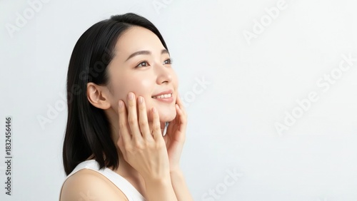 Close up of a young Asian woman's face showing her gentle touch on her cheeks and a happy expression chinese korean japanese