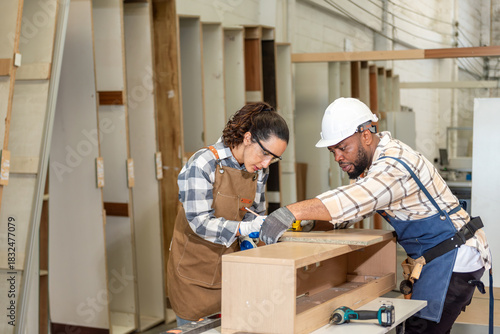 Two colleague young aged carpenter standing aim equipment tool for wood furniture at wood plank in workshop. coworker carpenter working craft with wood diy tool in workbench shop carpentry