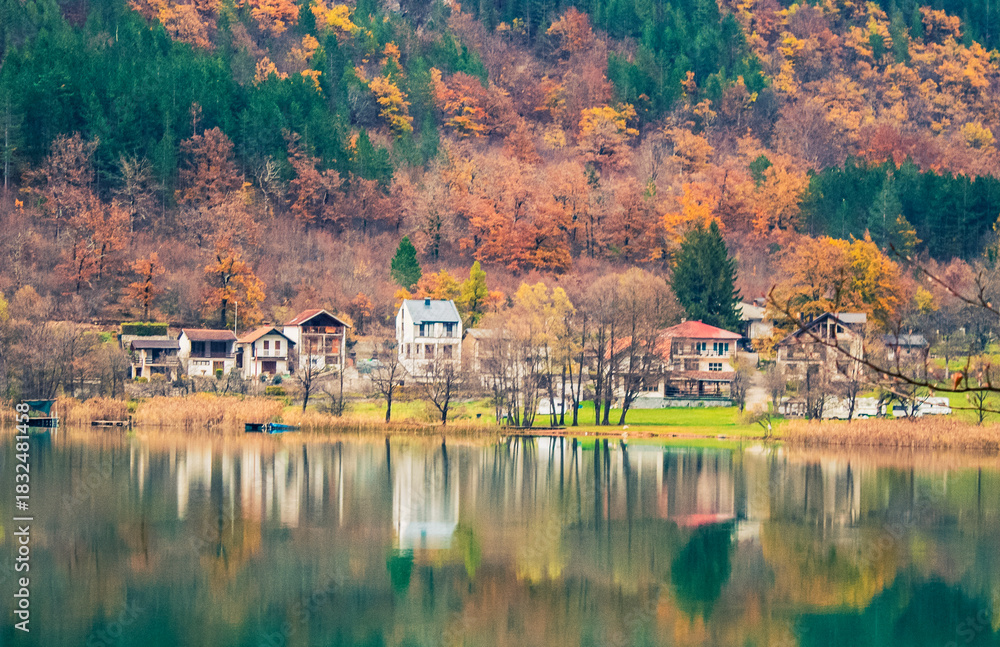 Fototapeta premium Scenic lake view in Herzegovina with cabins, abstract composition emphasizing water reflections and mountain silhouettes