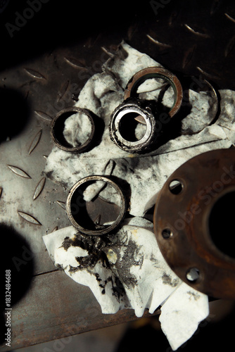 Replacing a wheel bearing in a classic car. Old vehicle restoration concept. Worn wheel bearing on a dirty, oily napkin. Metal textured background.