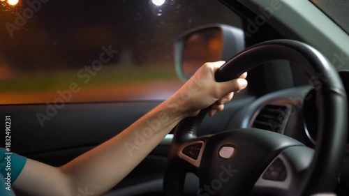 closeup of hand driving a car with wet and blurred windows and beautiful city light
