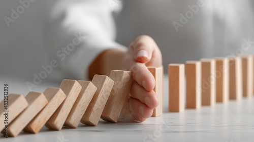 A hand stopping falling wooden blocks symbolizing prevention, risk control and the proactive actions required to avoid negative consequences in critical situations.
