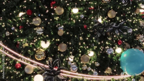 In the background, a glowing Christmas tree decorated with red and gold baubles ornaments and blue ball perfectly captures the joyful spirit of the holiday season