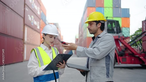 A male engineer discusses job details via walkie-talkie before passing it to a female colleague in a container yard. The bustling setting showcases effective teamwork in logistics.