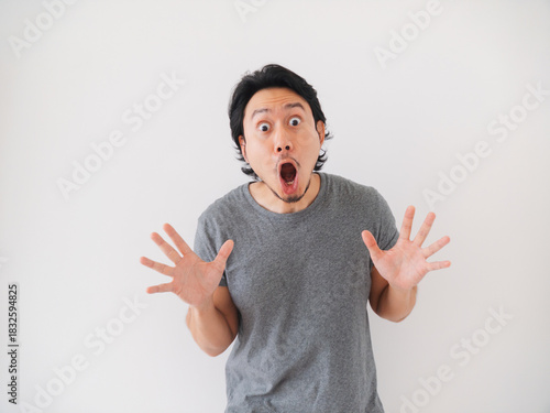 Happy and surprise reaction of Asian man in grey t-shirt isolated on white.