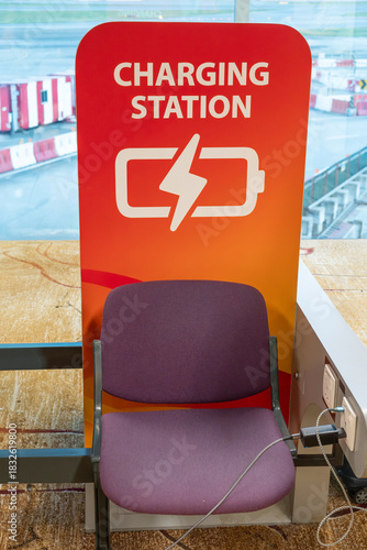 Charging station at Changi Airport in Singapore with a bright red sign featuring a battery icon and a lightning bolt symbol. 