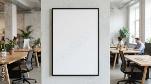 Blank Poster Mockup Frame on a Textured Wall, a Clean and Modern Office Workspace with Blurred Colleagues, a Productive Environment