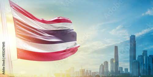 Thailand flag wavering in beautiful clouds with building skyline. The flag with drone shot in beautiful sky. Thailand national flag for independence day.