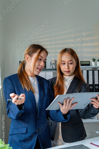 Businesswoman sitting at desk on couch in workplace or at home working on laptop and analyzing data on charts and graphs and writing on papers to make business plan and strategies for company, 