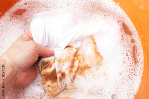 Soaking stained white clothes in detergent for laundry and hygiene
