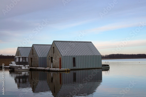 A beautiful view of a lake with water houses and sunrise under a cloudy sky