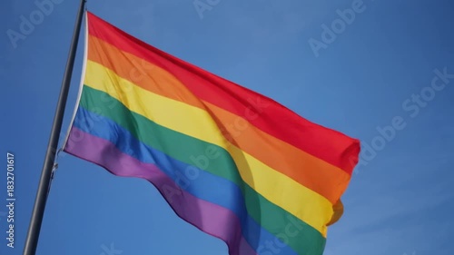 Rainbow flag waving in blue sky, symbol of pride and equality, perfect for LGBTQ celebrations and awareness campaigns