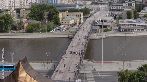 Aerial view of Patriarch's Bridge over the Moskva River in Moscow, with people walking on it and city buildings in the background.