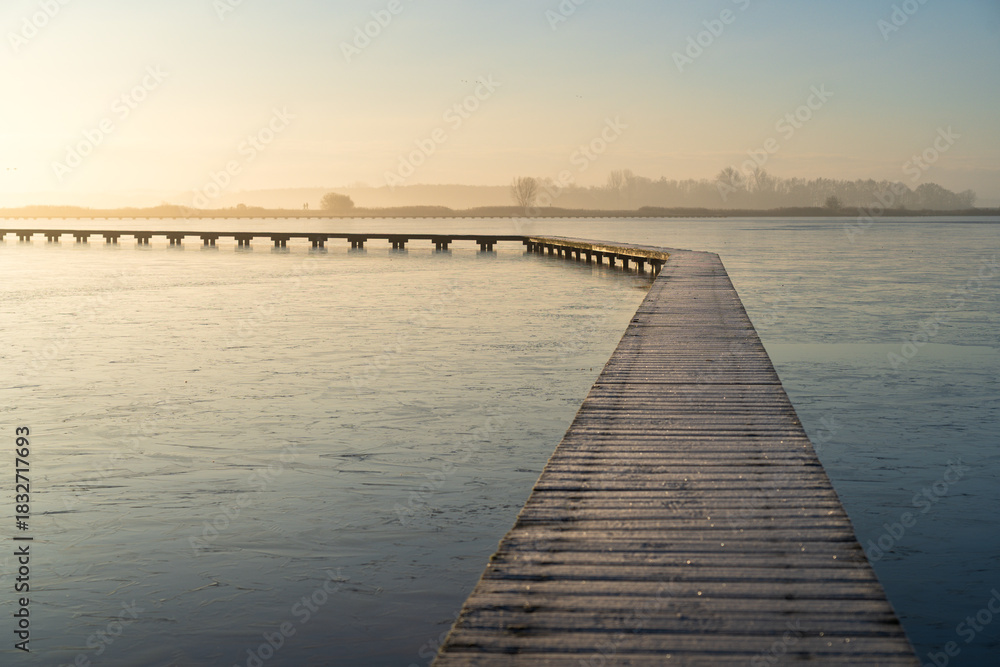 Fototapeta premium Hoarfrost on a jetty (Knuppelpad) in nature reserve Roegwold during a cold, autumn sunrise.