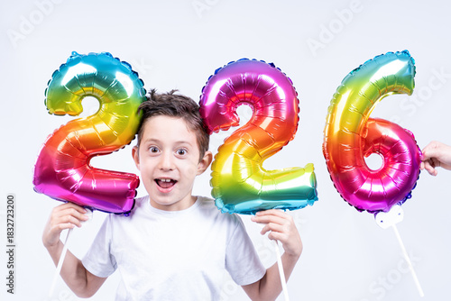 A little boy holds colorful balloons showing the coming new year 2026