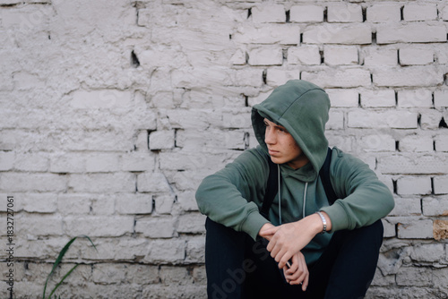 Young man feeling sad and lonely against brick wall