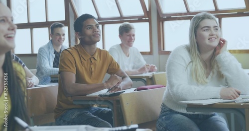Studying six students writing at wooden desks in classroom, wearing fuzzy sweater and mustard polo