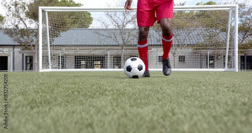 Bild auf Leinwand Standing adult player in red shorts and knee-high socks controlling soccer ball