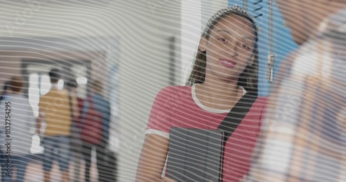 Leaning teen student holding gray binder, wearing pink tee and bag strap by blue school lockers