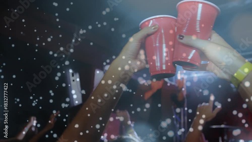 Singer singing music under lights, camera pushing crowd, hands raising red cups clinking toasting