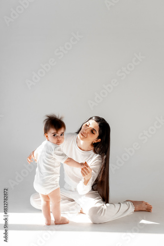 a mother holds her baby's hands as she teaches him to walk, the first steps, space and room for text, mother and child, maternal love