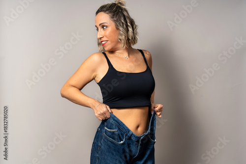 Woman showing significant weight loss results wearing oversized jeans