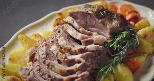 freshly baked pork neck tenderloin and baked potatoes on big white plate, food closeup