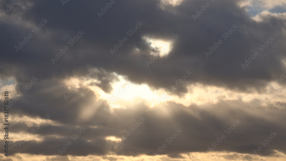 Obraz premium Sunbeams break dramatically through dense clouds in the sky.