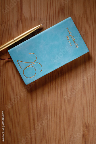 2026 planner and gold colored pen on wood background
