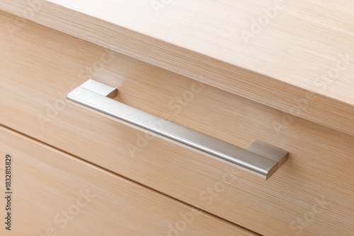 Metal cabinet handle on wooden kitchen cabinet. Original innovative stainless steel door handle. Furniture Doorknob. Interior design. Drawer cup handles cabinets parts. Front view minimalist design.