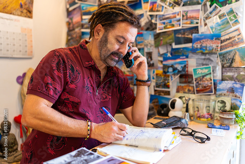 Hispanic man on phone call organizing tourism reservations at his travel agency