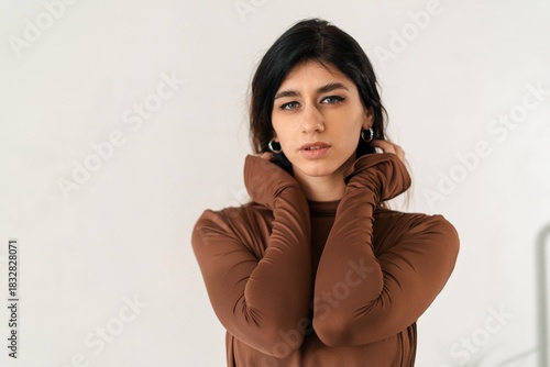 Portrait of a woman in a brown long-sleeve dress on a light background
