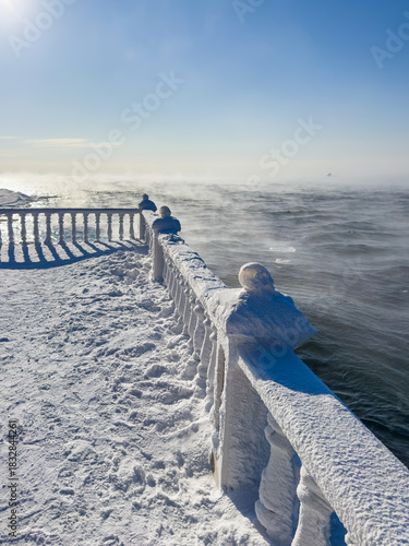 Winter landscape. Cold fog over the river on snowy riverside.