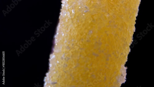 Two-tone Yellow and Red Marmalade Candy rotating on black. Macro view of layered Lemon and Strawberry jelly covered in sugar. Bicolor sweet dessert.