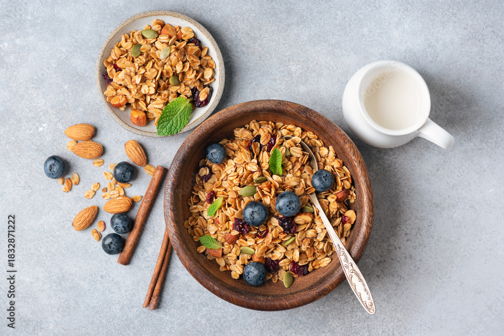 Fototapeta premium Homemade crunchy oat honey granola with raisins and nuts in wooden bowl, rich in fiber breakfast cereals