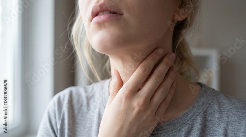 Unwell young woman touching her sore throat, feeling pain and discomfort