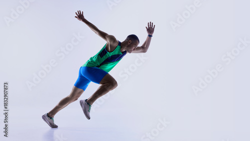 Runner advancing from crouched start into acceleration phase. Concept of sprint technique guides, athlete development programs, coaching materials, and sports product promotions.