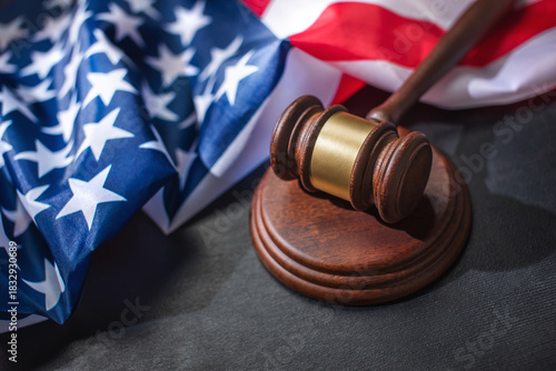 Fotografie A judge gavel on sound block with American flag on a black surface, symbolizing justice and patriotism