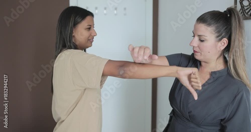 Chiropractor doing arm exercise to young woman to ensure correct body posture - Medical and healthcare concept