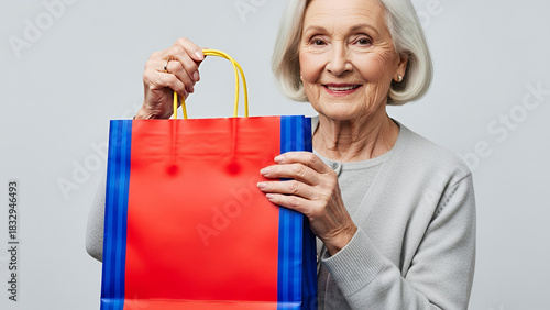 Grandmother happily holding a bright red gift bag with colorful handles
