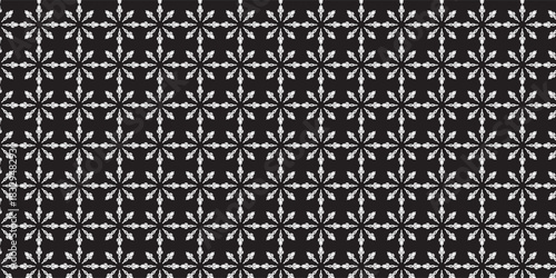 A seamless pattern of white, intricate snowflake shapes arranged in a uniform grid on a black background, creating a crisp and elegant winter-themed design.